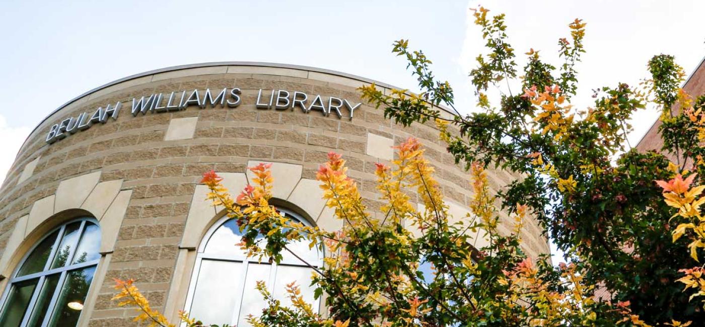 Top of the Beulah Williams Library Round Room exterior with fall-color tree branches visible