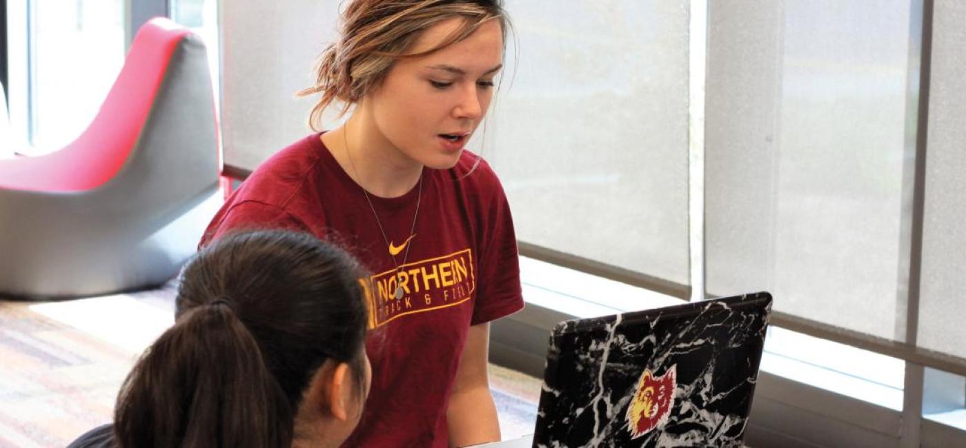  A student on a laptop talks to another student