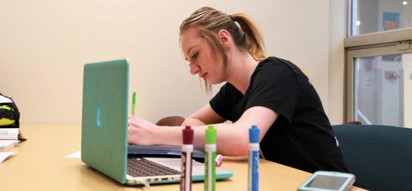A student leans over a laptop
