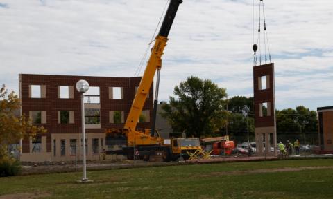 Photo of large crane standing up one wall of building