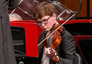 Isaac Seaton plays violin during an orchestra performance