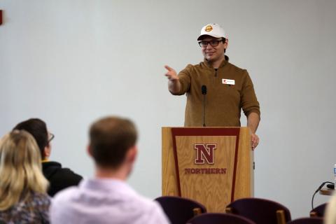 A speaker gestures behind a Northern podium