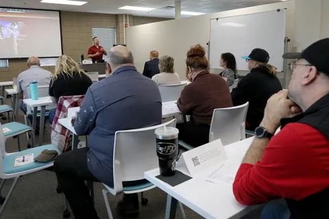 People at a marketing workshop view a presentation and listen to a speaker