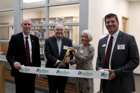 Four people posing for a picture at a ribbon cutting ceremony