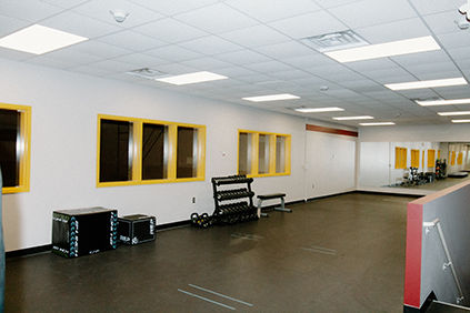 Northwest view of the fitness studio. The image shows free weights, plyometric boxes, an area for medicine ball exercises, and a mirror.