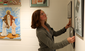 NSU student hanging artwork in new gallery