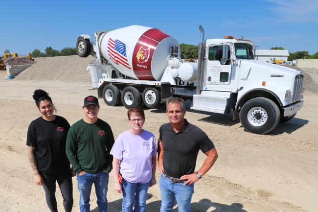 Four people standing in front of a cement truck