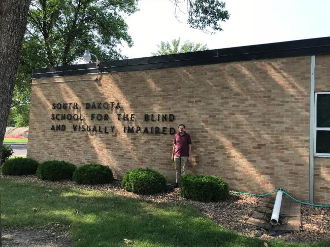 Man standing in front of the South Dakota School for the Blind and Visually Impaired