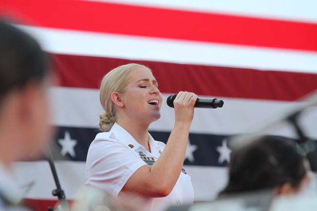 Female soldier singing in front of an American flag