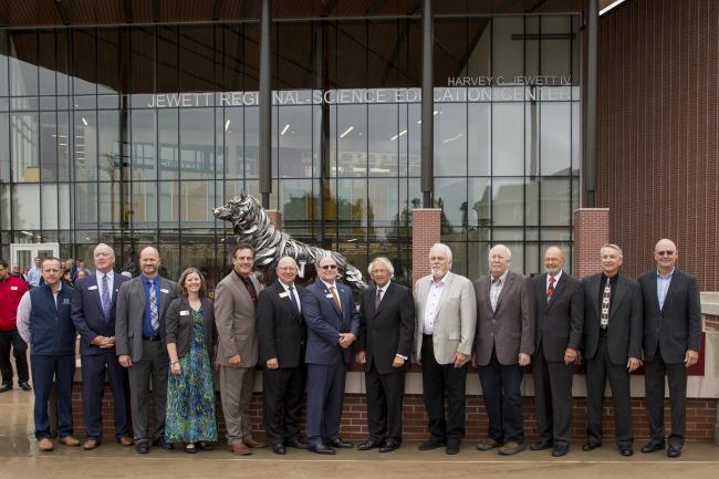 Several officials standing in front of the wolf sculpture at the Regional Science Education Center