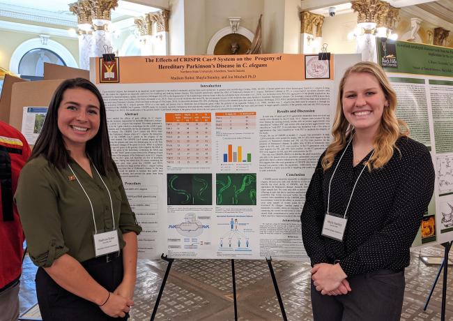 Two female students standing in front of their research poster