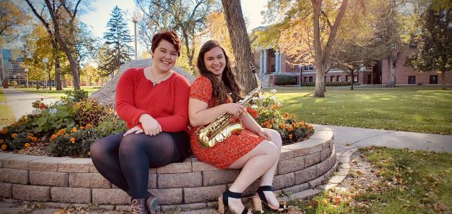Two young women sitting outside on college campus