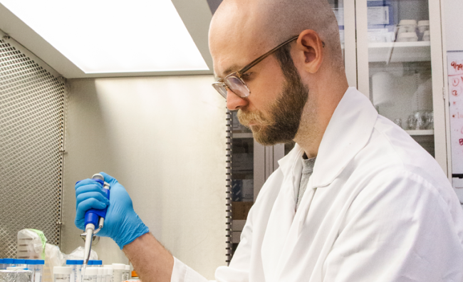 Male college student in white lab coat conducting scientific research