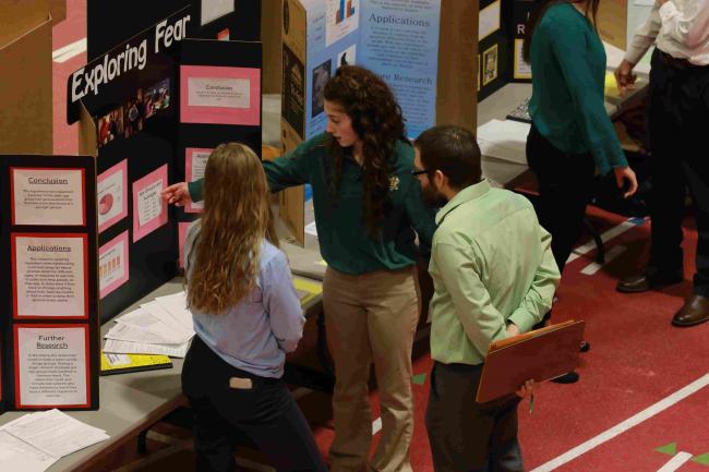 Student showing science project to judges