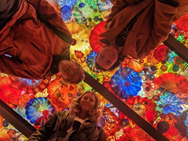 A view looking up at Dr. Jon Mitchell and students Grace Kramer and Kennedy Davis with a colorful display behind them