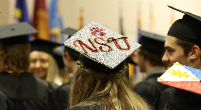 A graduation hat is bejeweled to say NSU with a wolf paw above it
