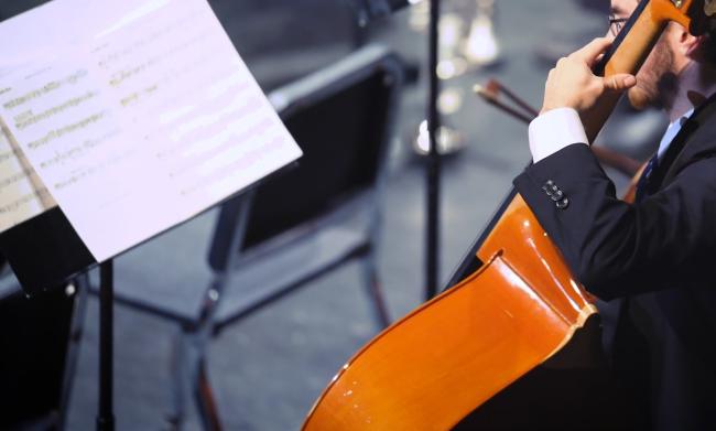 Close up on a bass player and a stand of sheet music