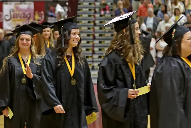 Students in graduation attire walking in a line-up