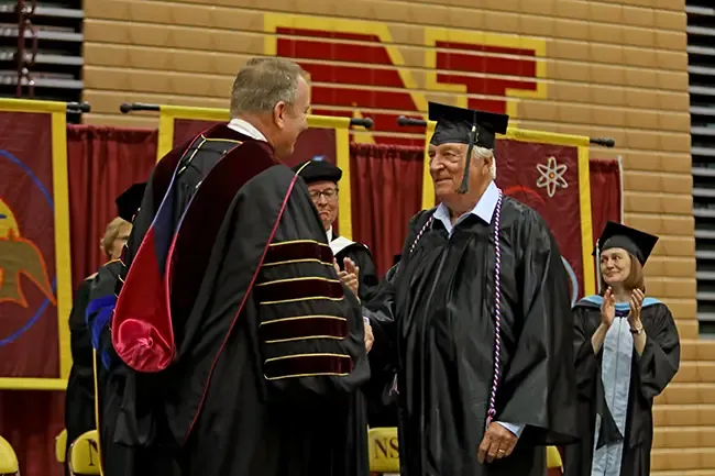 Ronald Meland walking across the commencement stage at Northern State University